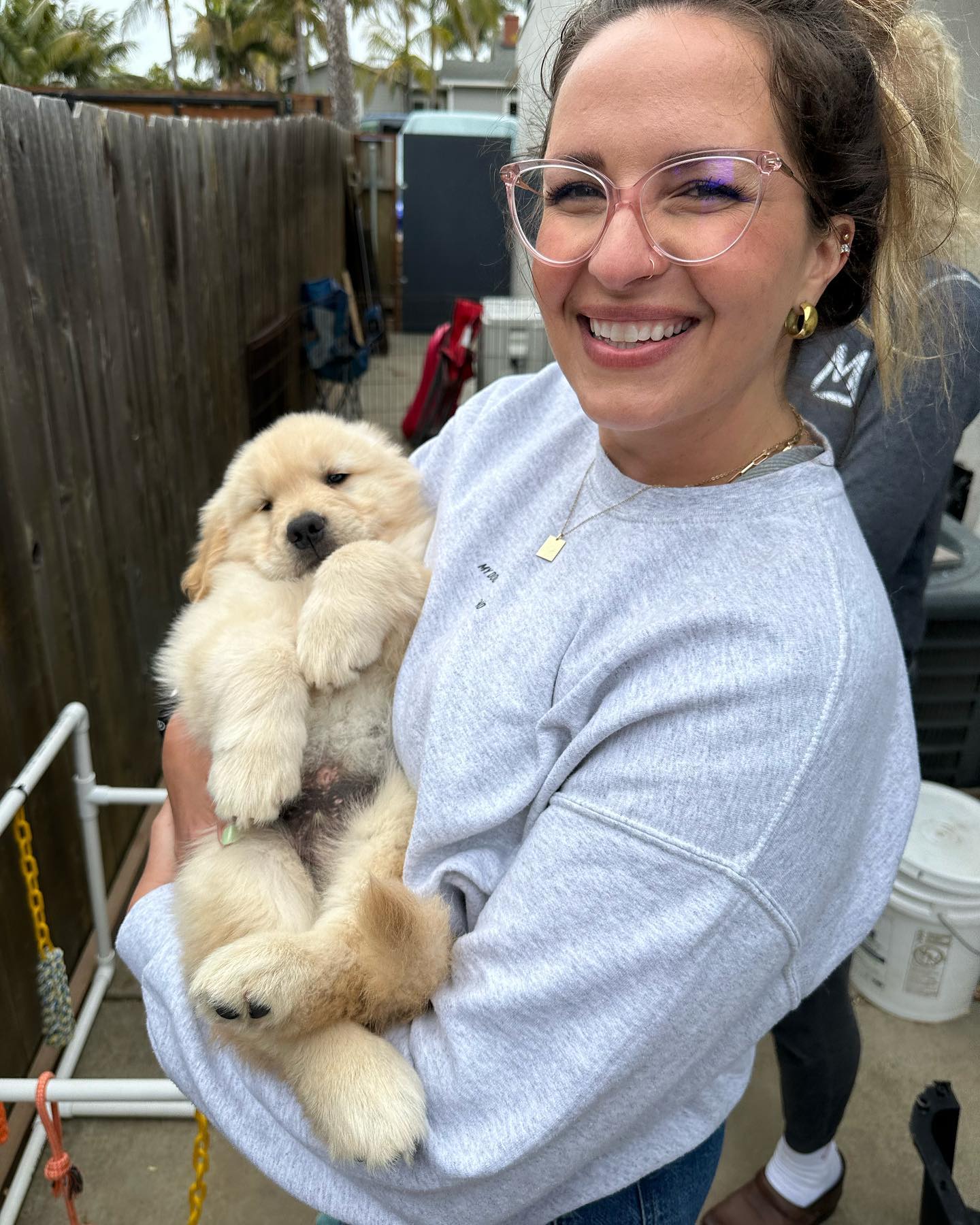 Woman smiling while holding a golden puppy.